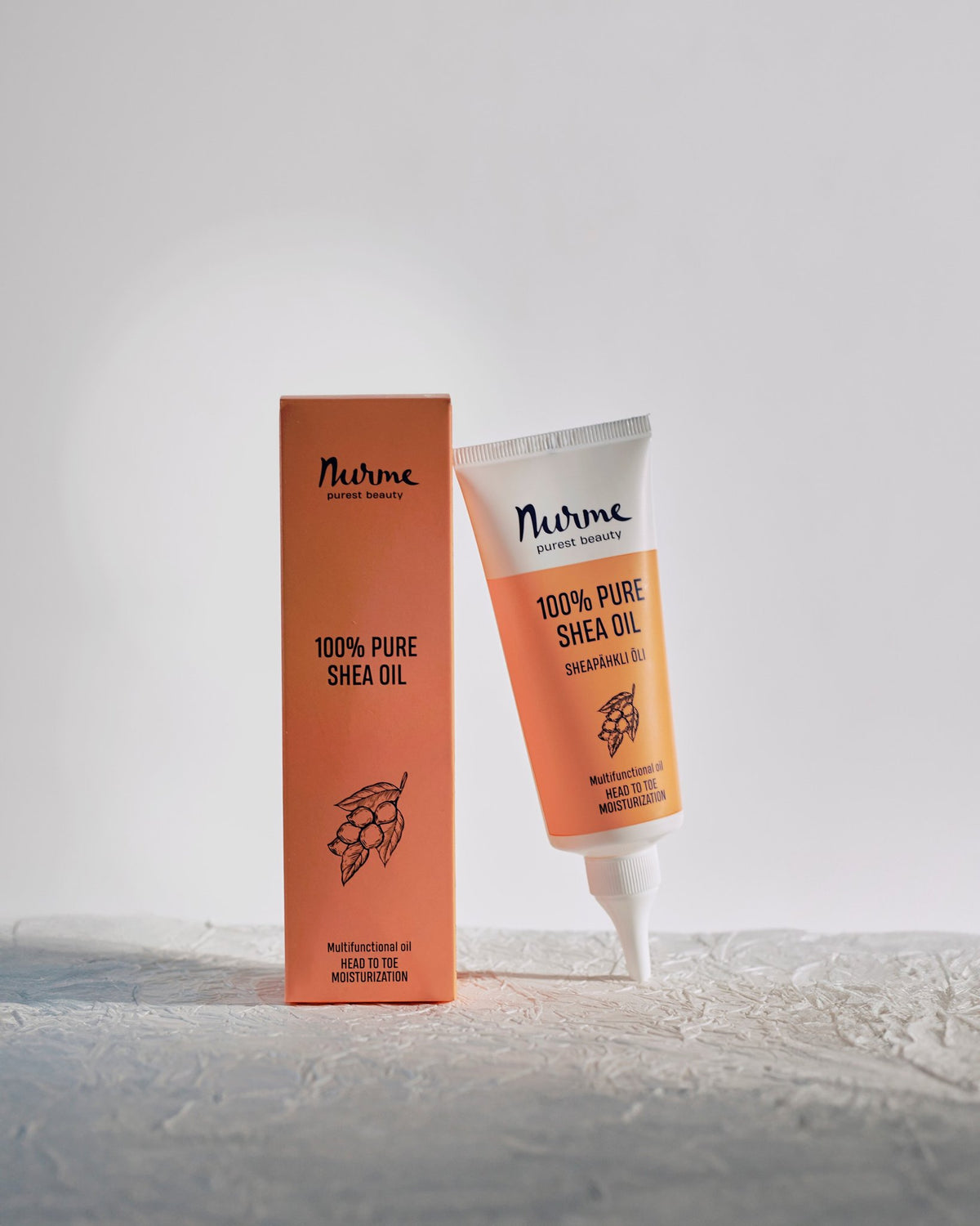 1. Nurme 100% Pure Shea Oil in eco-friendly twist cap tube with packaging on textured surface