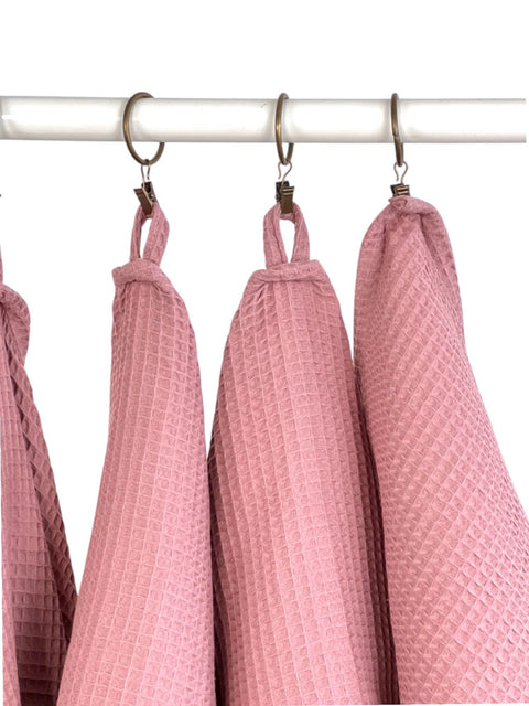 5. Close-up of old pink waffle cotton towels hanging on hooks, focusing on texture and loops