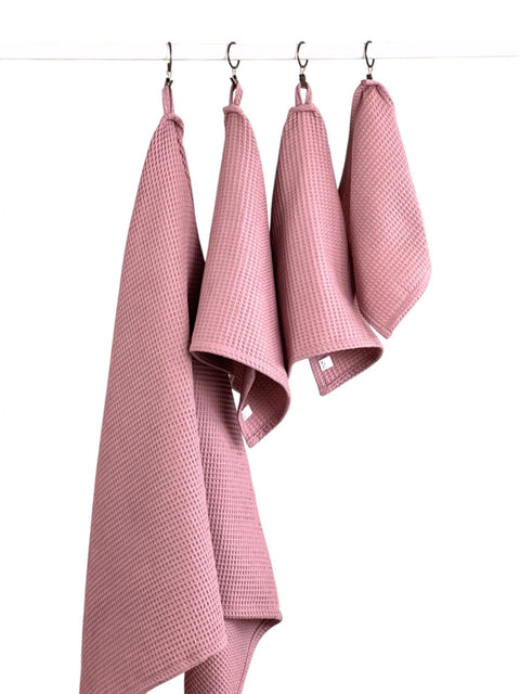 4. Old pink waffle cotton towels in various sizes hanging on a rod, highlighting texture