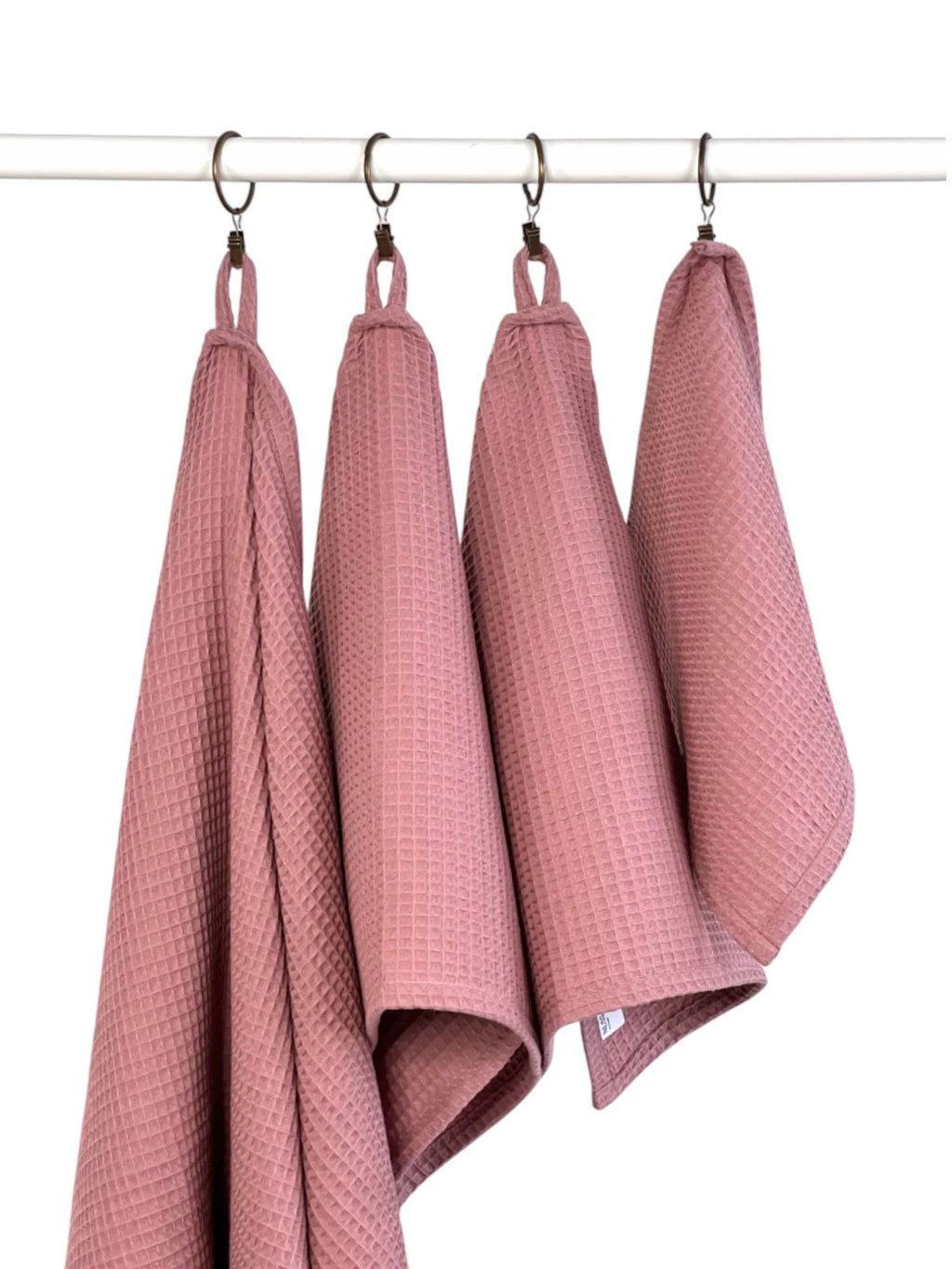 3. Four old pink waffle cotton towels hanging on hooks, showing different sizes