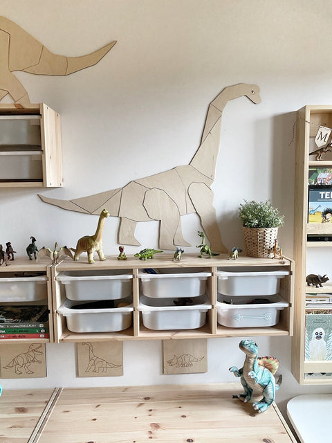 1. Child's room with wooden origami diplodocus wall decoration above storage shelves with dinosaur toys and books