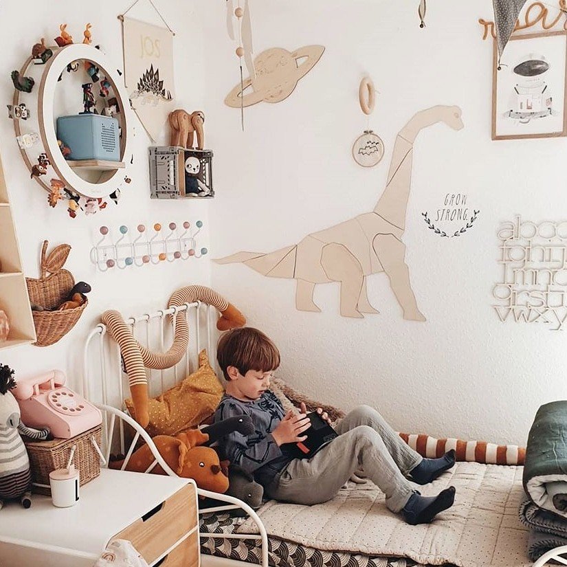 5. Boy sitting in room with wooden diplodocus wall decoration and playful decor