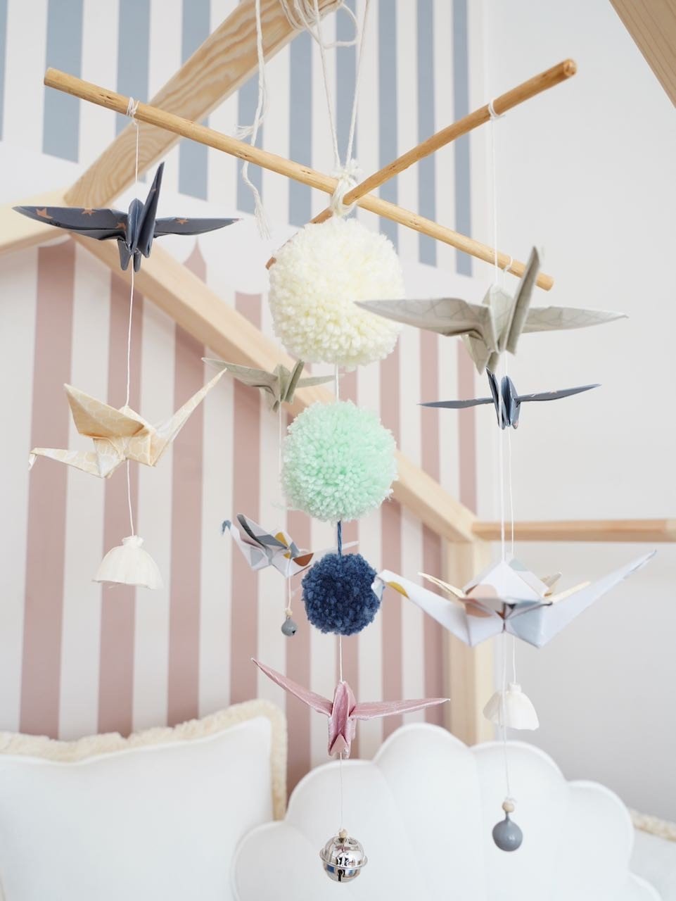 2. Moi Mili pastel origami mobile with paper cranes, pompoms, and wooden sticks in a nursery setting