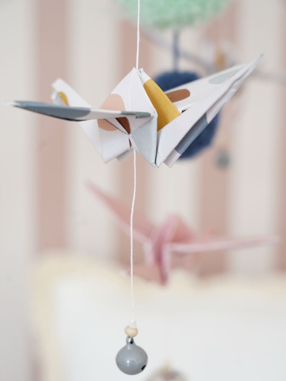 4. Detailed view of origami crane and pompom on Moi Mili pastel nursery mobile