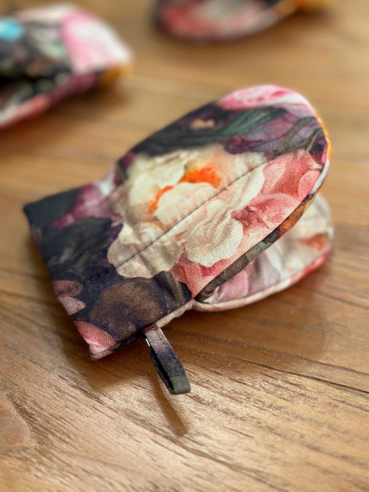 1. Floral printed oven glove with double wool filling on wooden surface, showcasing elegant design and craftsmanship