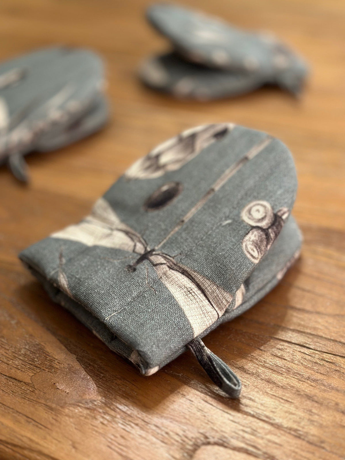 1. Close-up of Hortensias Home oven glove in seeds aqua print with double wool filling on wooden surface