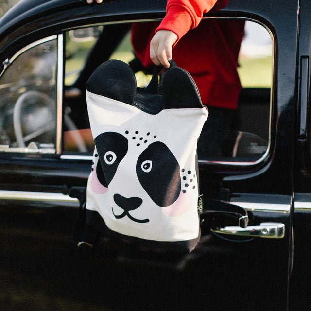 11. Muni Panda backpack being held out of a car window, showcasing its playful design