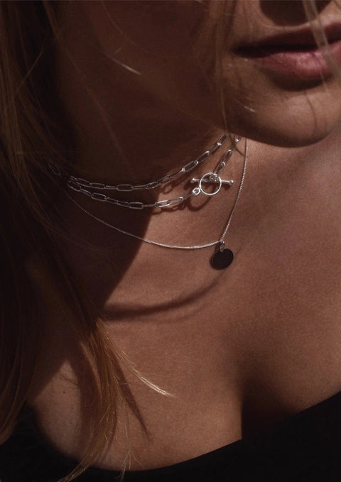 1. Women's layered silver paper clip choker by NO MORE, styled with additional necklaces, shown in lifestyle setting
