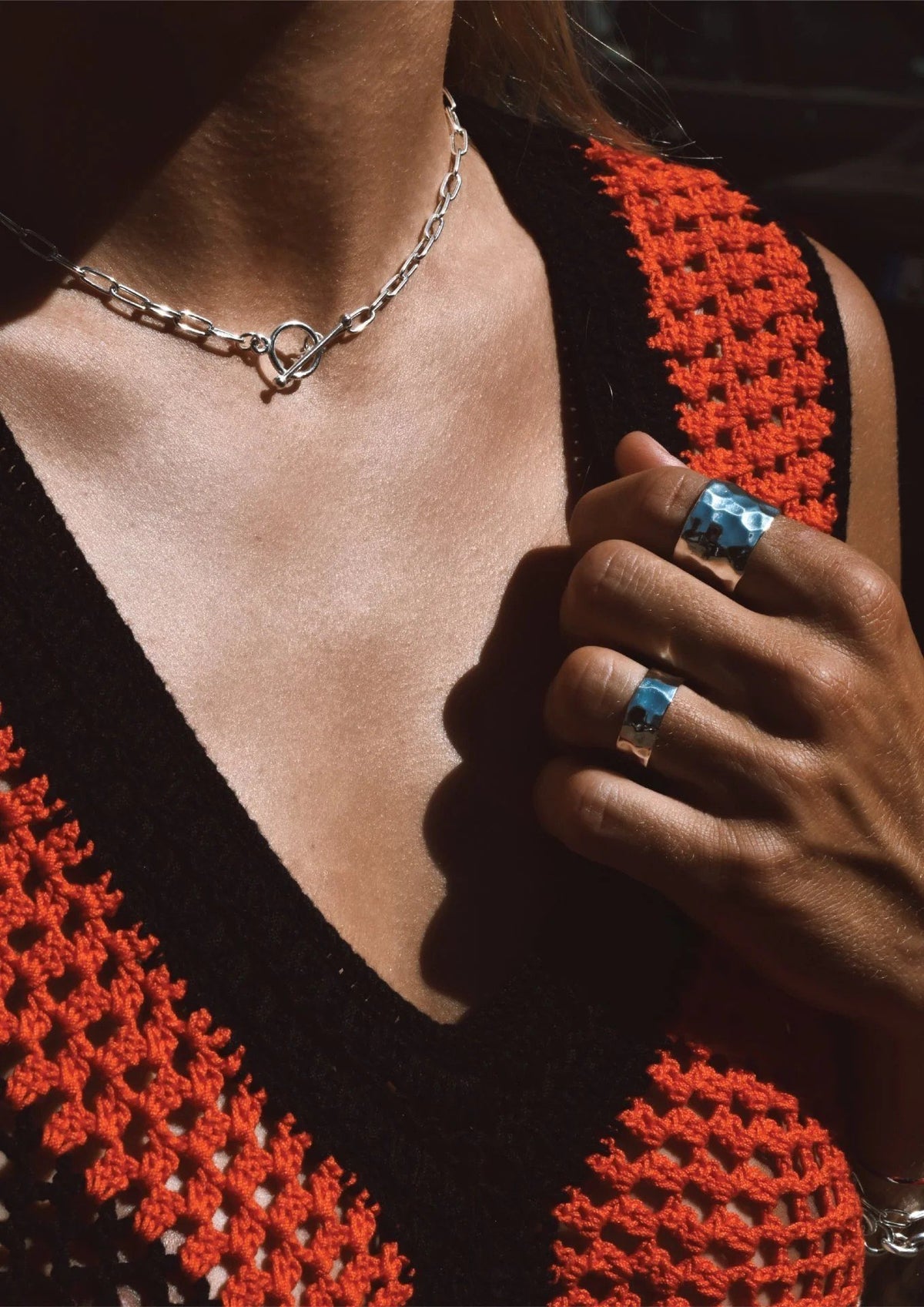 3. Woman wearing NO MORE silver paper clip choker with crochet top and silver rings, shown in lifestyle setting