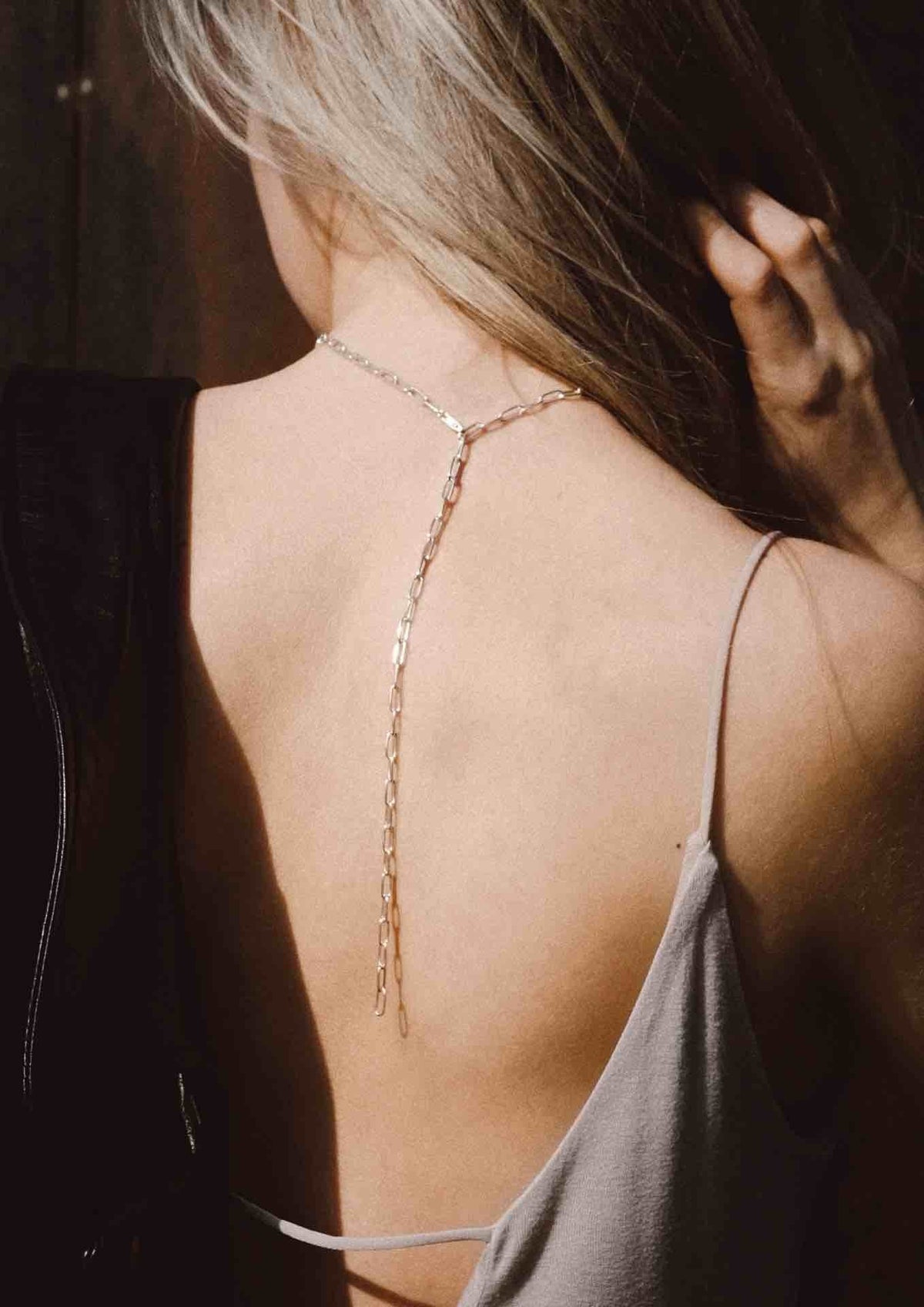 7. Back view of woman wearing silver Y-shaped necklace with open back dress