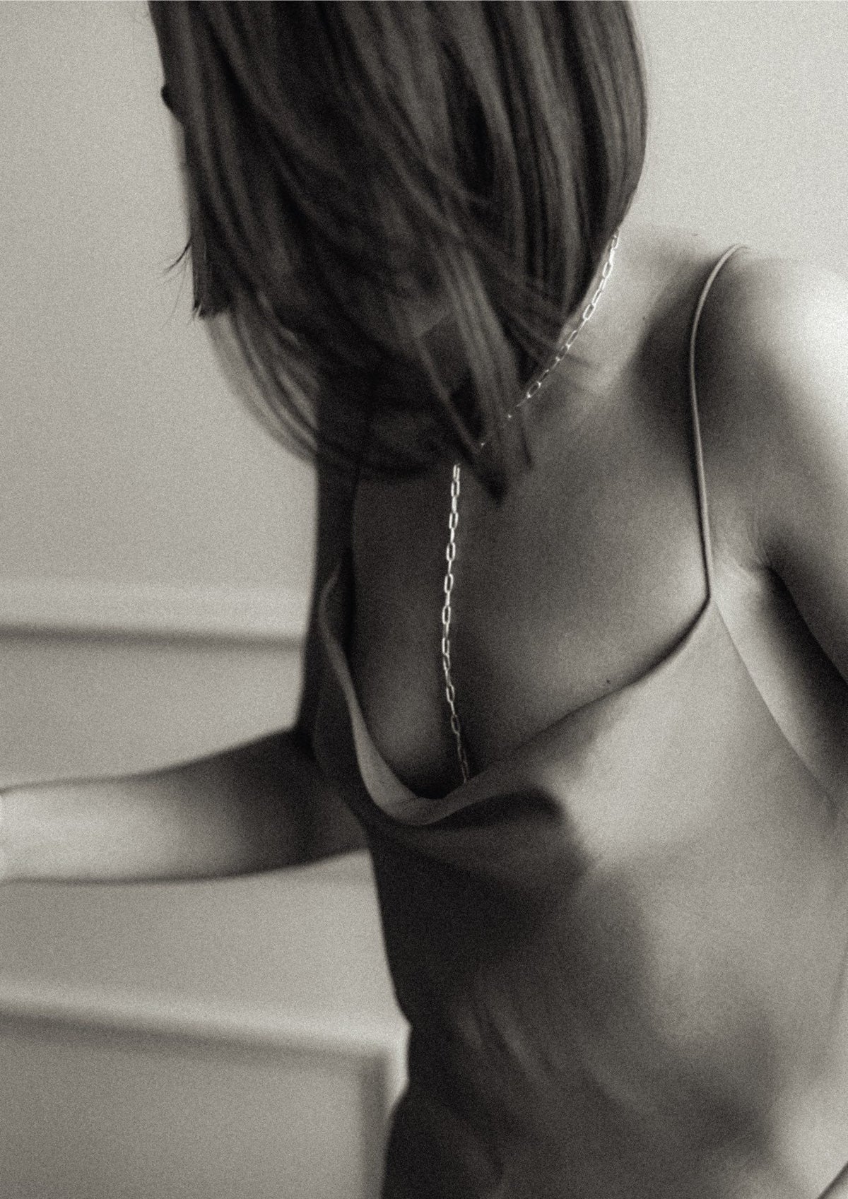 8. Black and white image of woman wearing silver Y-shaped necklace with open back dress