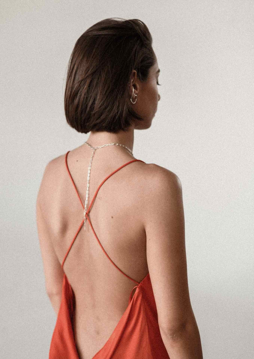 9. Back view of woman in red dress wearing silver Y-shaped necklace