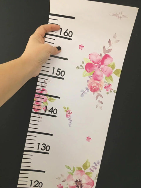 3. Close-up of hand holding floral growth chart showing measurement scale and Little Harri logo