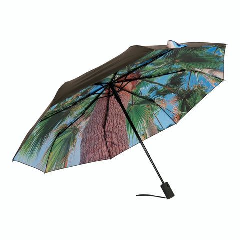 1. Open Paradise Umbrella with tropical print and black exterior, showcasing palm tree design against a clear sky
