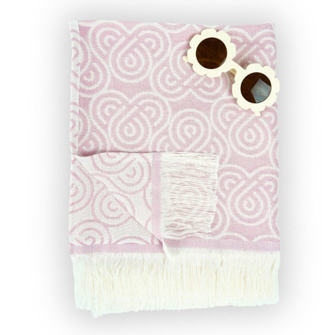 3. Flat lay of pink Patulove bamboo towel for kids with white fringe and floral sunglasses on top