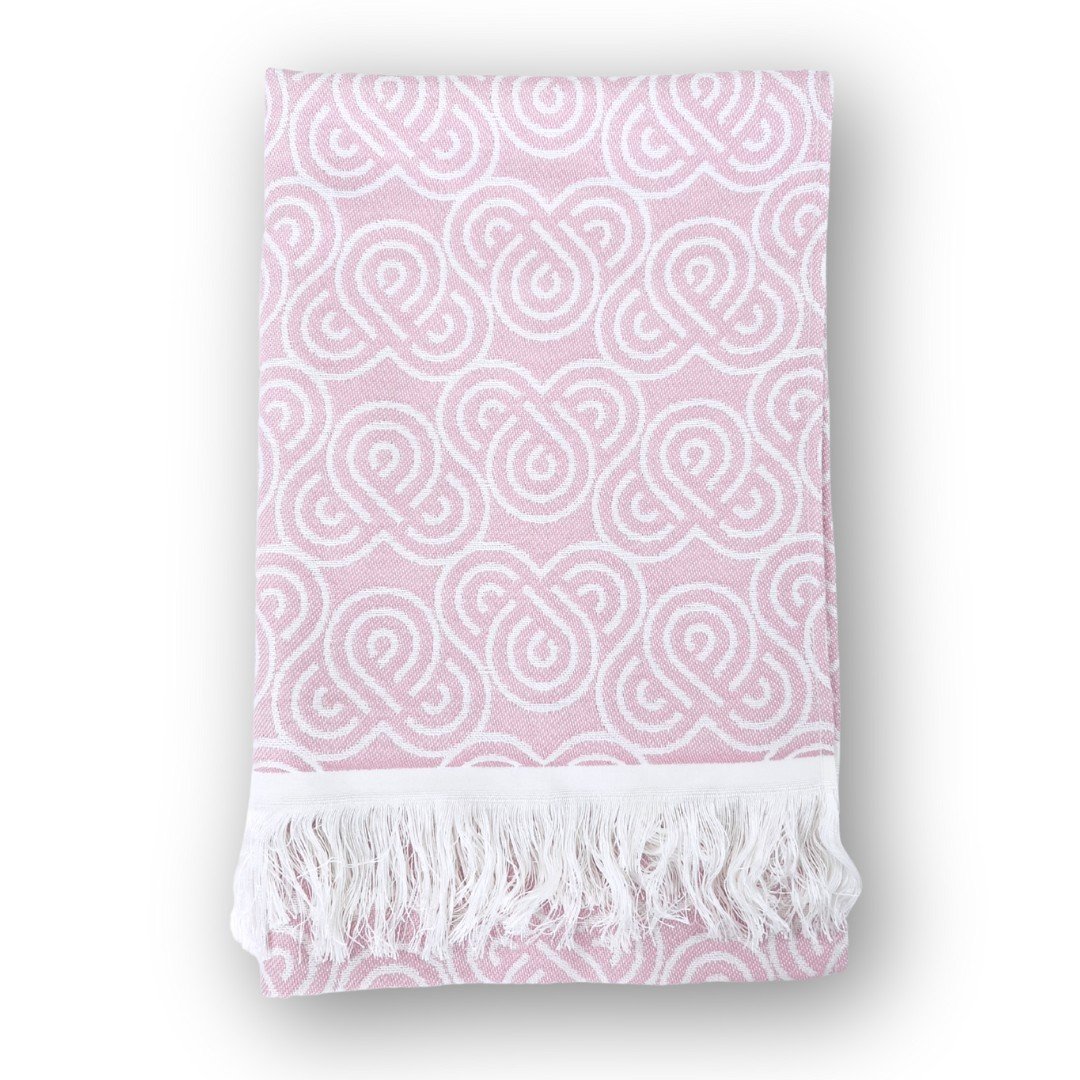 3. Pink bamboo towel with white loop pattern and fringed edges, folded on a white background