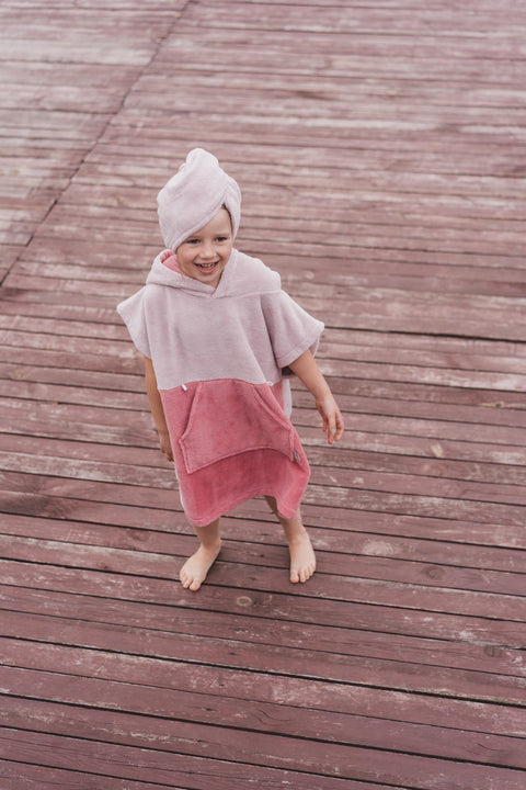 5. Child in pink bath poncho and hair turban standing on wooden deck