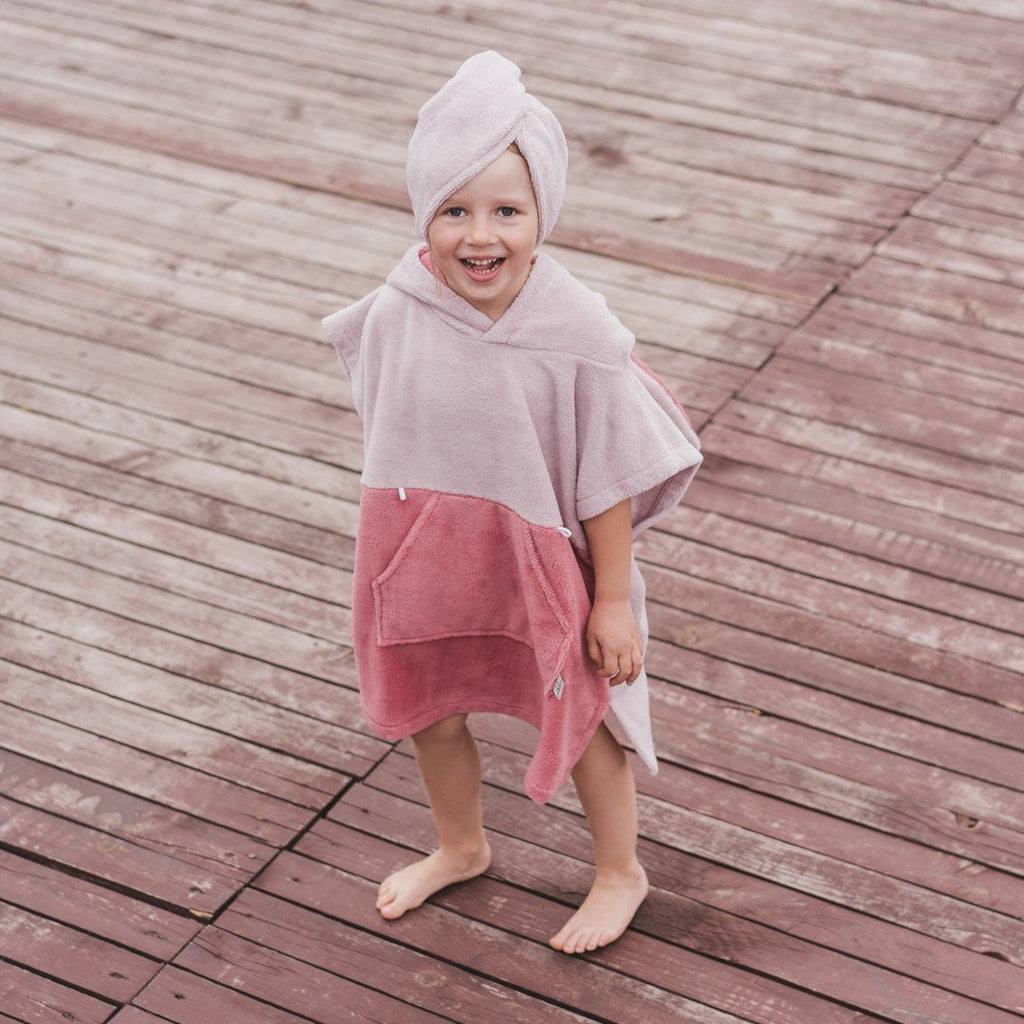 1. Child wearing pink bath poncho and bamboo-cotton hair turban on wooden deck