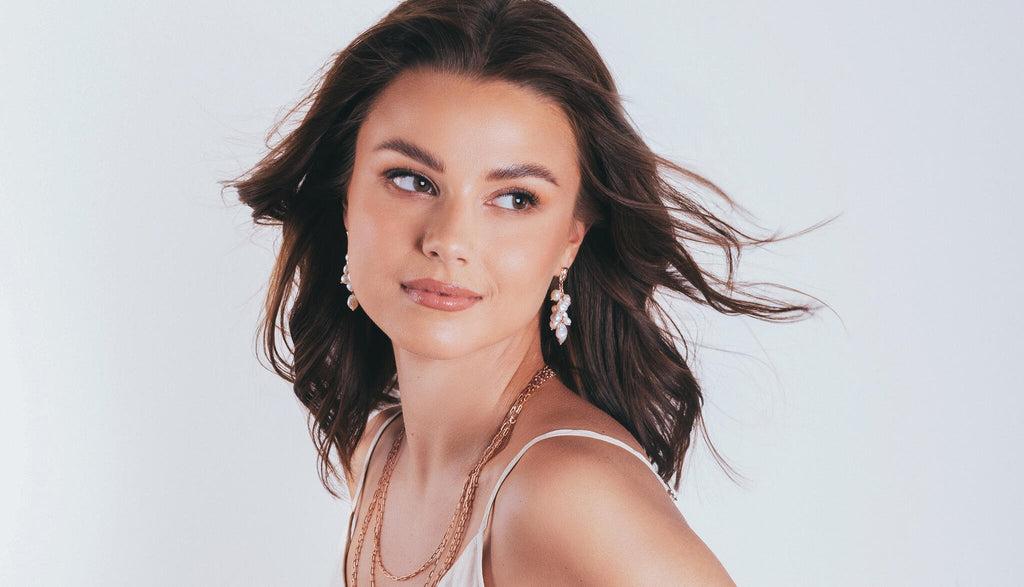 1. Woman wearing MyaMoon Festive Pearls Earrings in rose gold, showcasing elegant freshwater pearls in a lifestyle setting