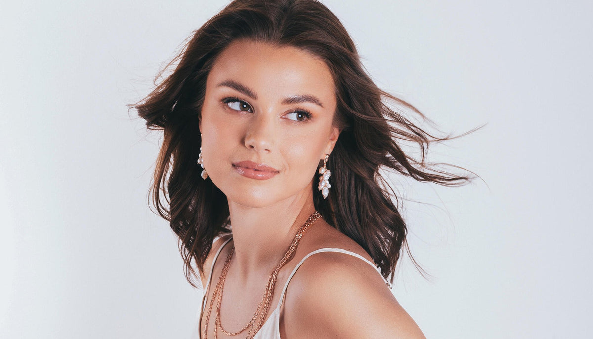 1. Woman wearing MyaMoon Festive Pearls Earrings in rose gold, showcasing elegant freshwater pearls in a lifestyle setting