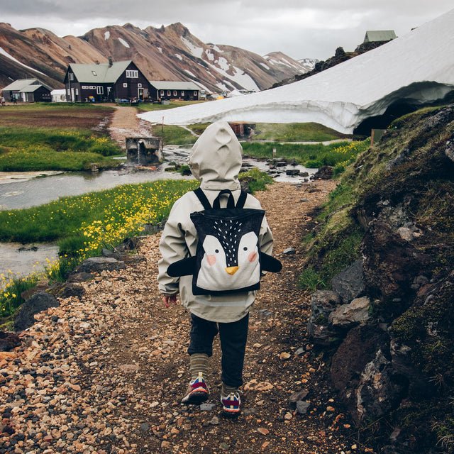 8. Kid wearing Muni Penguin backpack on a scenic outdoor trail