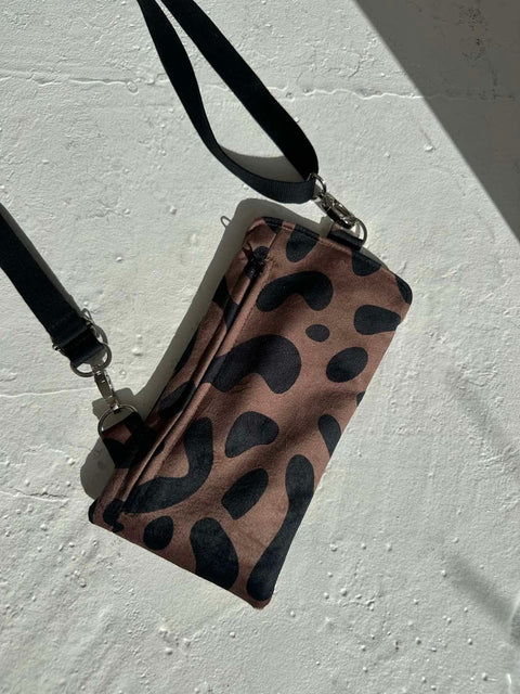 4. Flat lay of Garbanota classic leopard velour phone bag with adjustable strap on textured surface