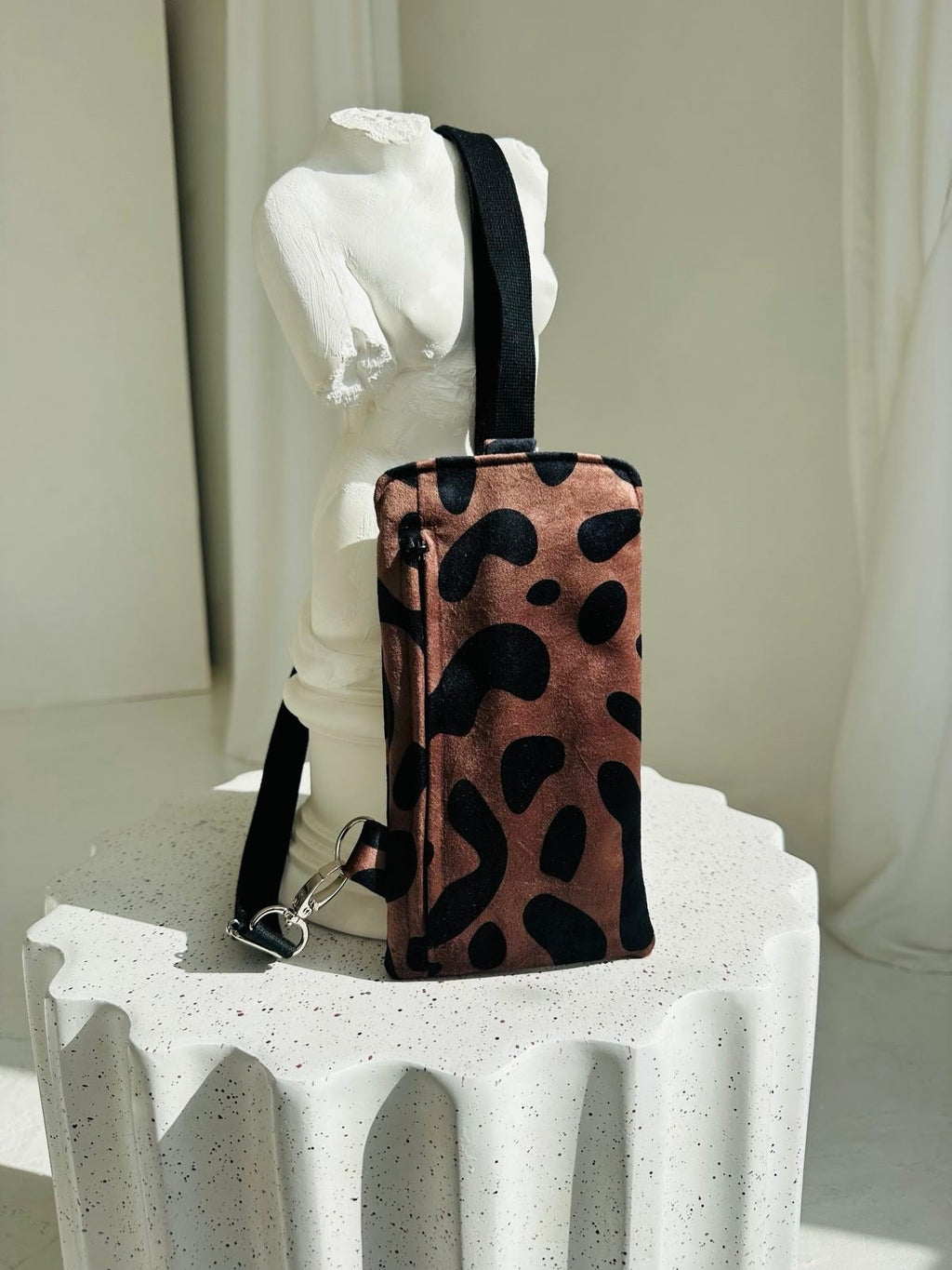 5. Garbanota classic leopard velour phone bag with adjustable strap displayed on white sculpture in studio setting