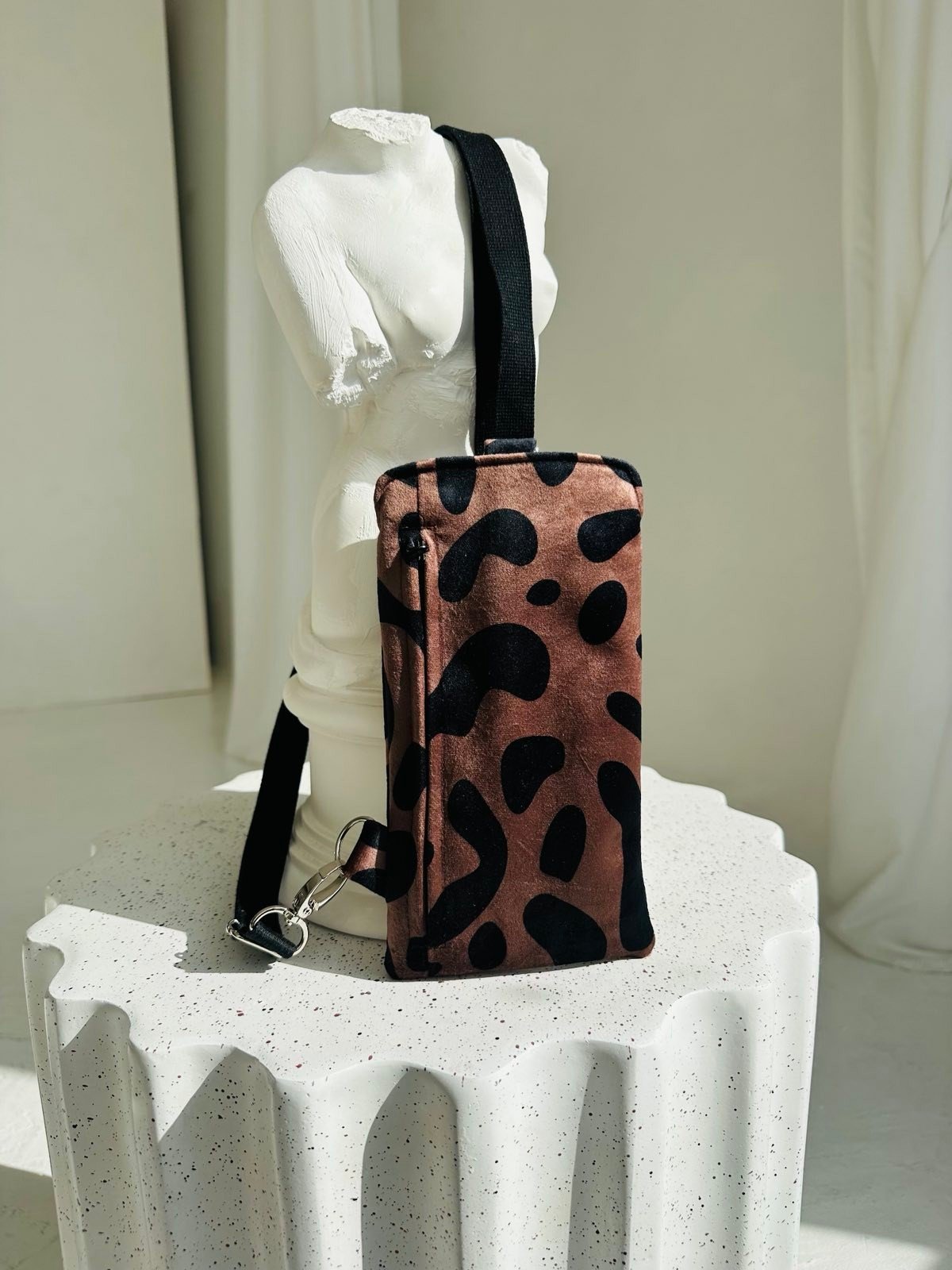 5. Garbanota classic leopard velour phone bag with adjustable strap displayed on white sculpture in studio setting