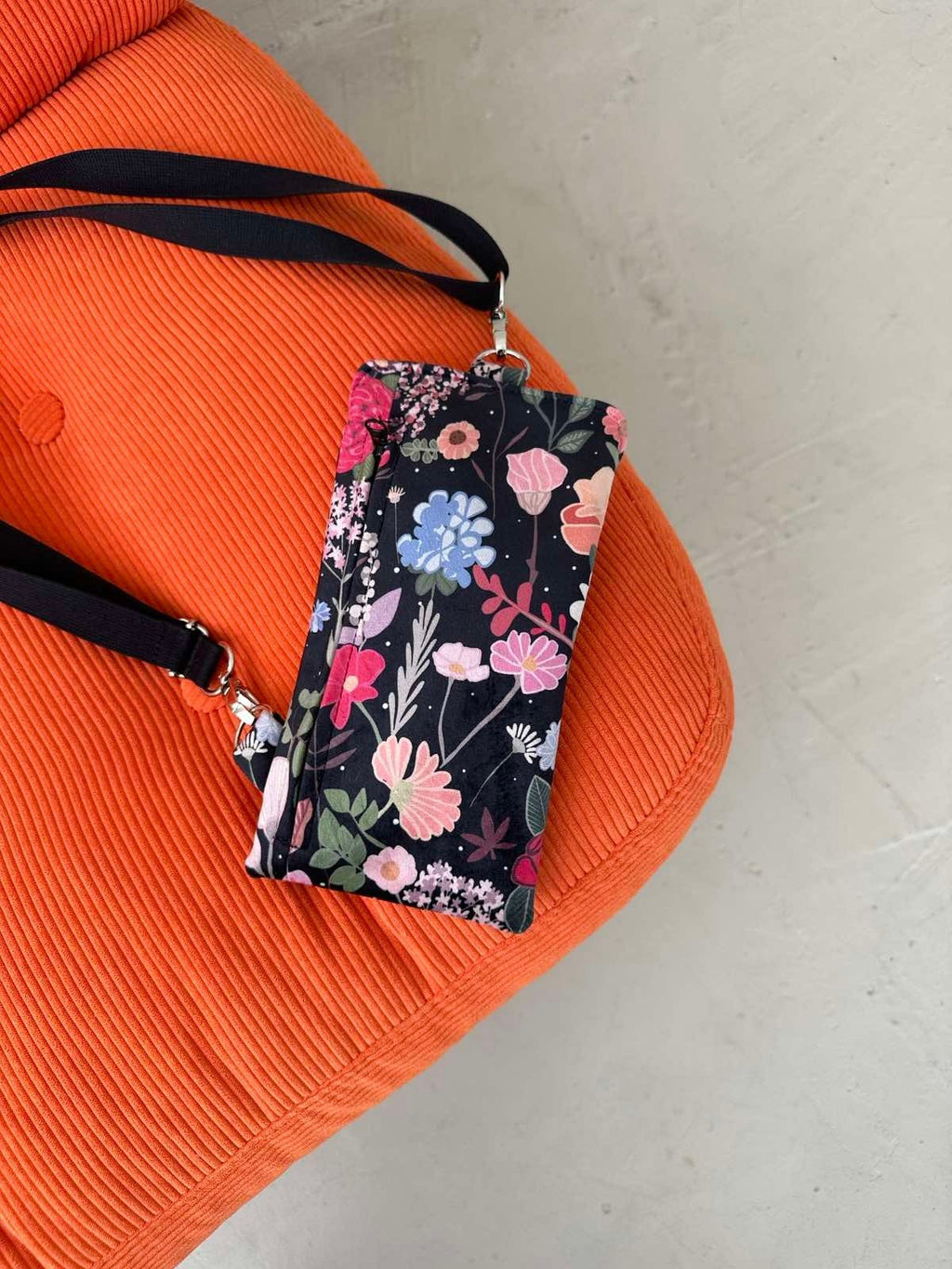 2. Garbanota Curly Summer Night phone bag with floral pattern on orange chair, showing adjustable strap