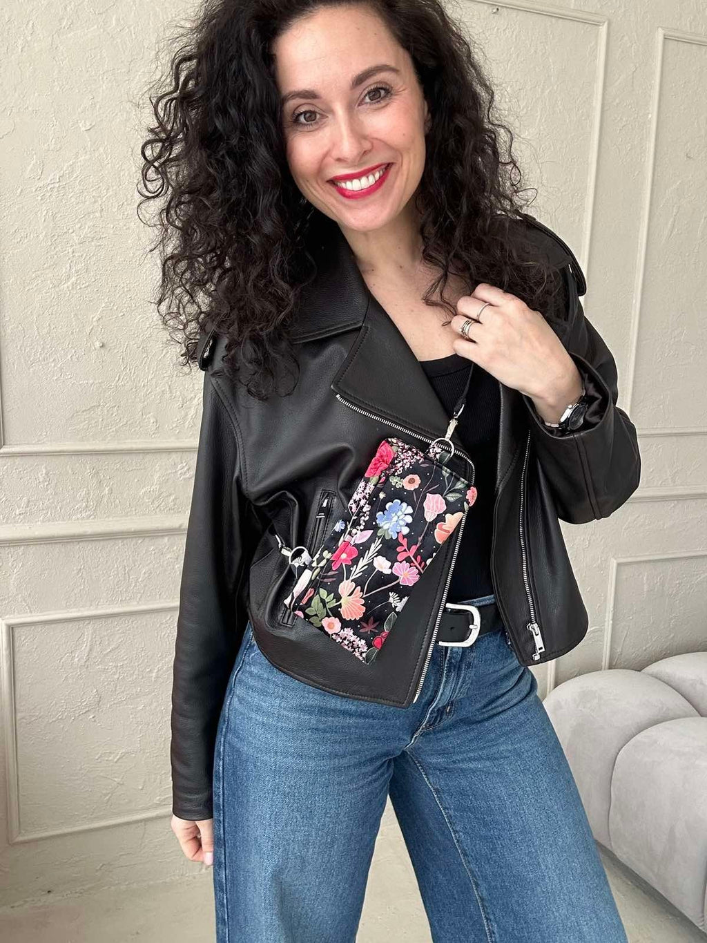1. Woman wearing Garbanota Curly Summer Night phone bag with floral design, styled with black leather jacket and jeans