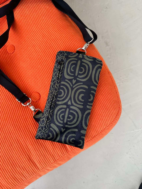 4. Close-up of Garbanota khaki pattern phone bag on orange fabric, showing pattern detail