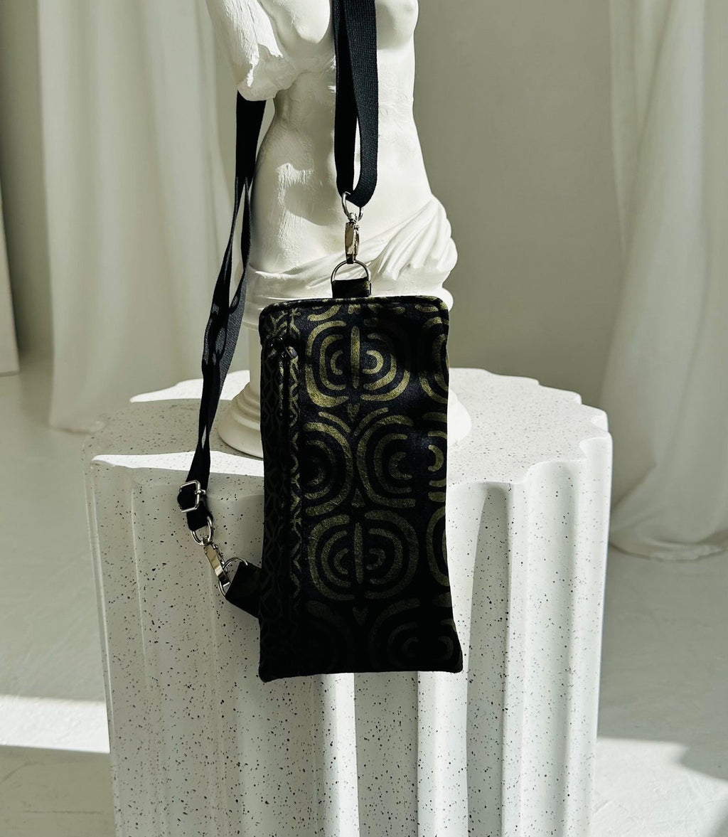 3. Garbanota khaki pattern phone bag displayed on white pedestal, highlighting design and strap