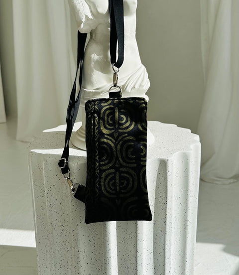 3. Garbanota khaki pattern phone bag displayed on white pedestal, highlighting design and strap