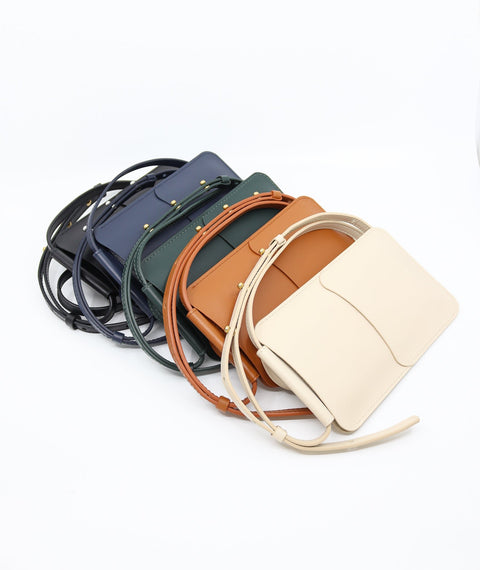 5. Flat lay of Tairi Roosve leather phone bags in various colors, including forest green, navy, and tan