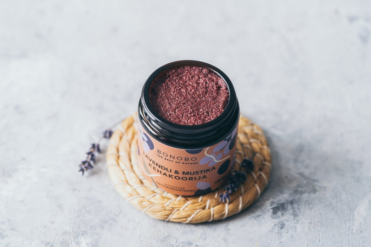 3. Open jar of BONOBO Blueberry & Lavender body scrub on a woven mat with lavender sprigs
