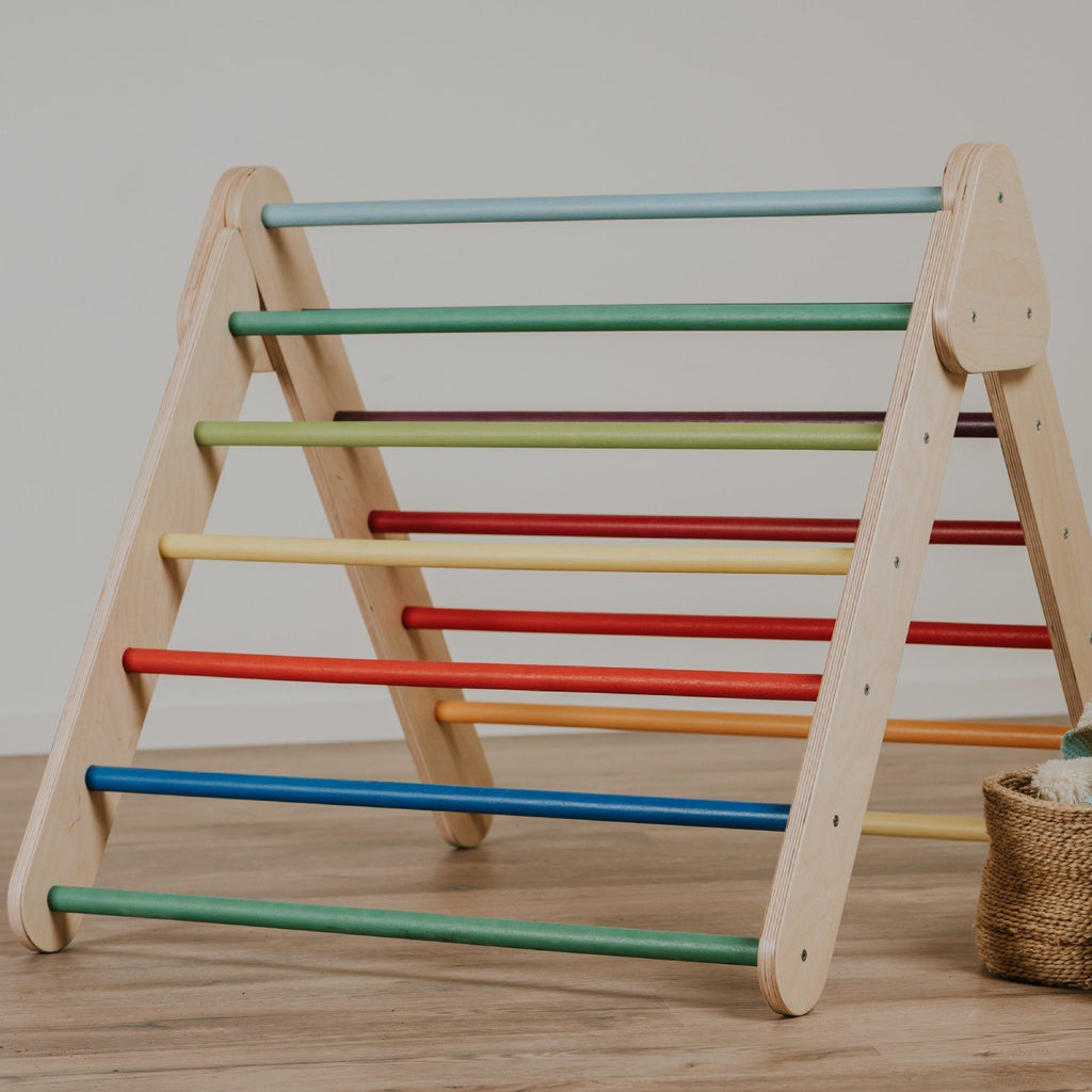 2. Studio shot of leg&go Pikler Triangle with rainbow-colored bars on wooden floor
