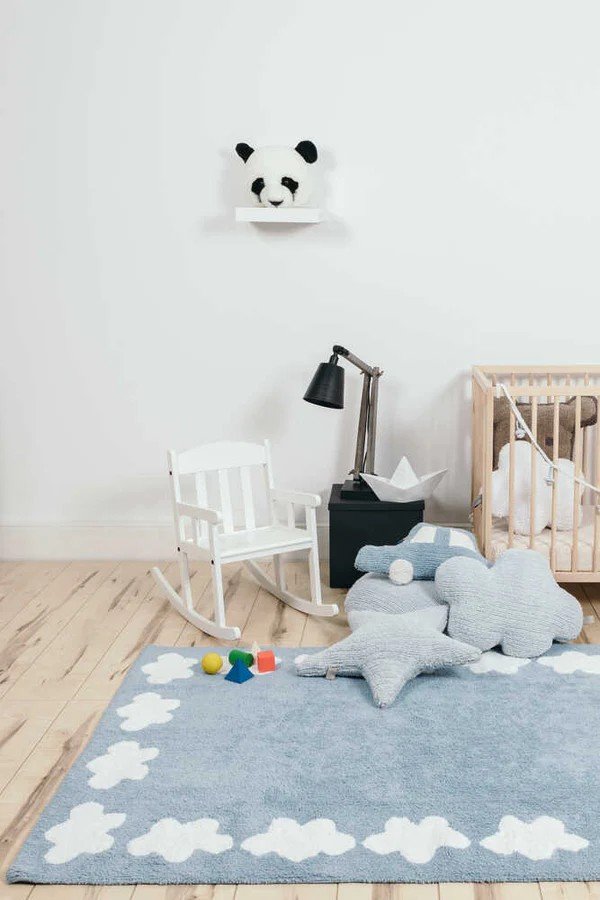 1. Children's room with blue cloud-shaped pillow on a cloud-patterned rug, next to a crib and rocking chair