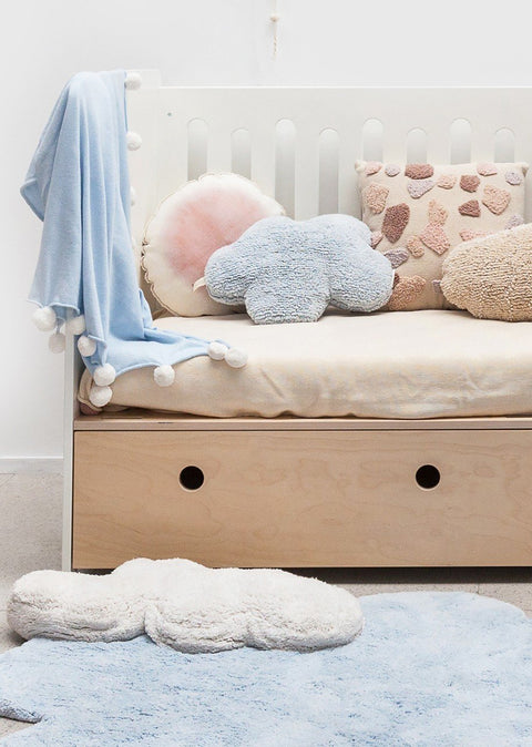 1. Blue cloud-shaped pillow on a bed with other decorative pillows in a cozy children's room setting
