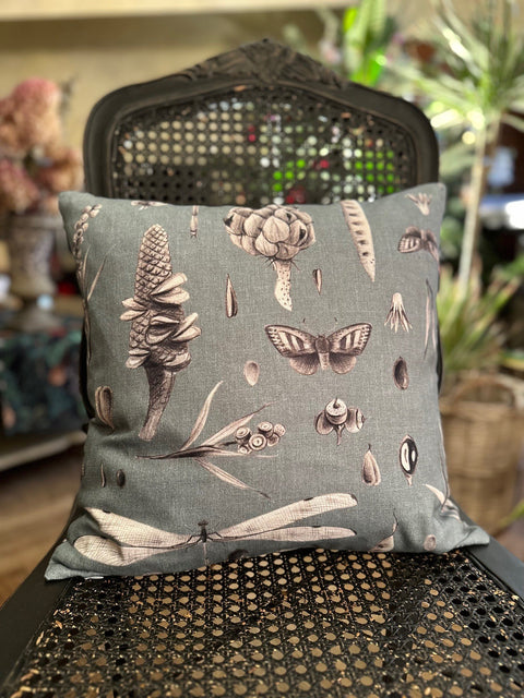 1. Decorative pillowcase with Seeds Aqua print on a chair in a cozy room setting, featuring botanical and insect illustrations, made from 100% cotton by Hortensias Home