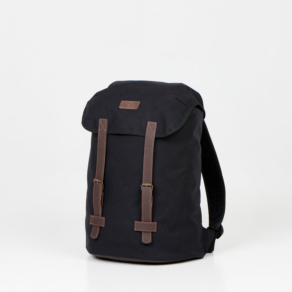 3. Angled view of Noel Cafe Handmade Backpack in black with brown detailing, studio setting