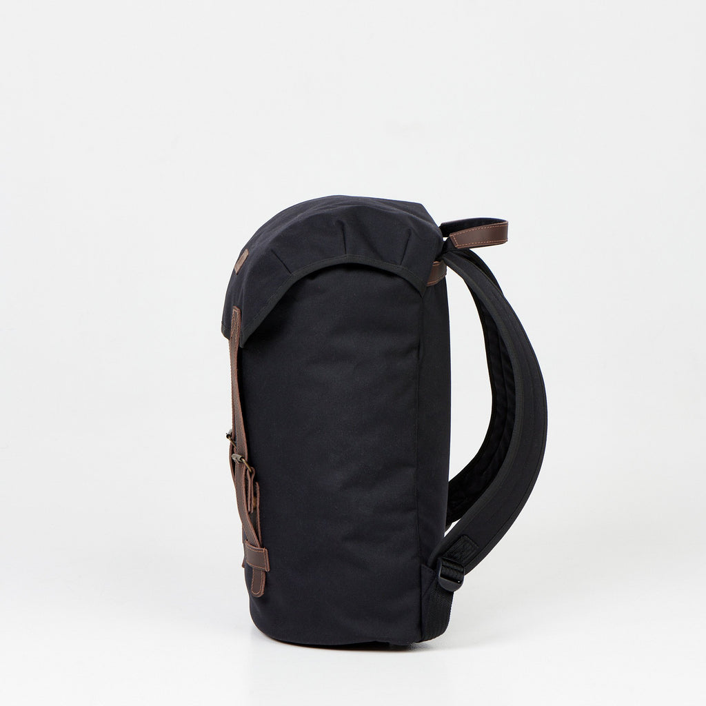 2. Side view of Noel Cafe Handmade Backpack in black, showing padded straps, studio setting
