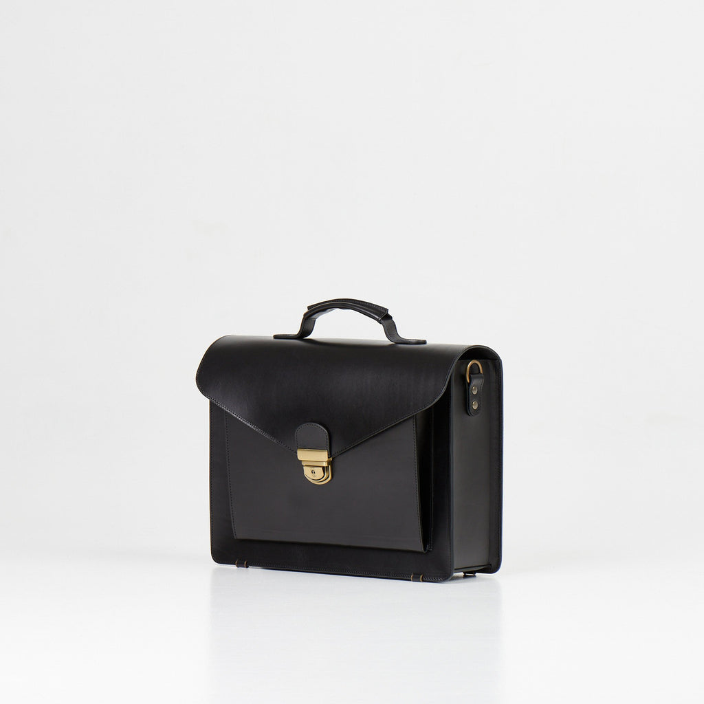 2. Papillon Briefcase No. 36 in black leather, angled side view showing clasp and handle, studio setting