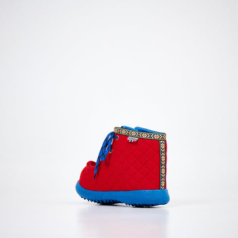 3. Back view of Nesna Lobben red felt boots with blue soles, highlighting decorative trim and quilted texture