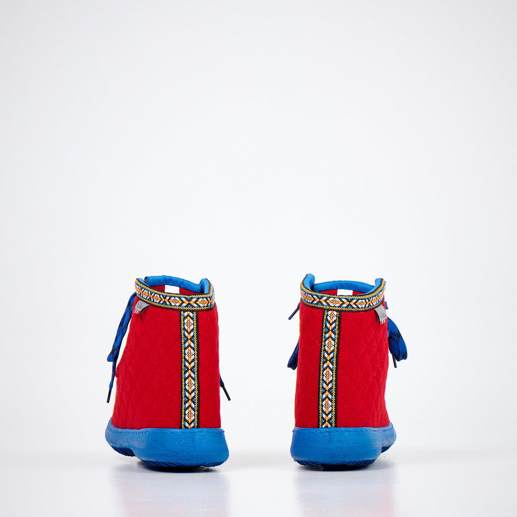 2. Side view of Nesna Lobben red felt boots with blue soles, showcasing quilted design and patterned trim