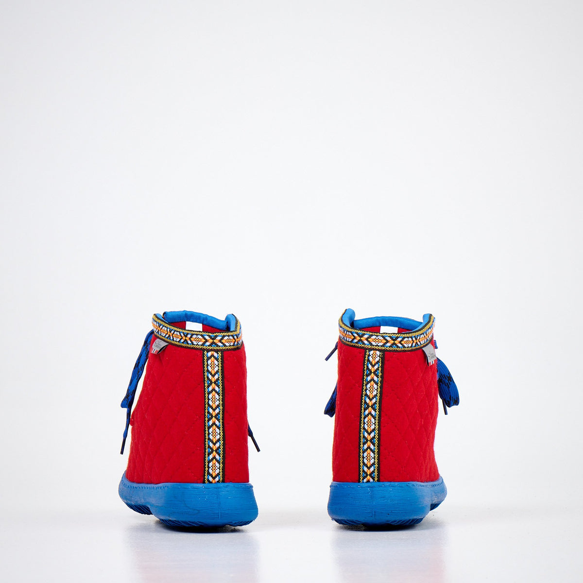 2. Side view of Nesna Lobben red felt boots with blue soles, showcasing quilted design and patterned trim