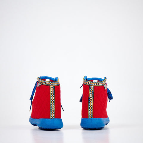 2. Side view of Nesna Lobben red felt boots with blue soles, showcasing quilted design and patterned trim