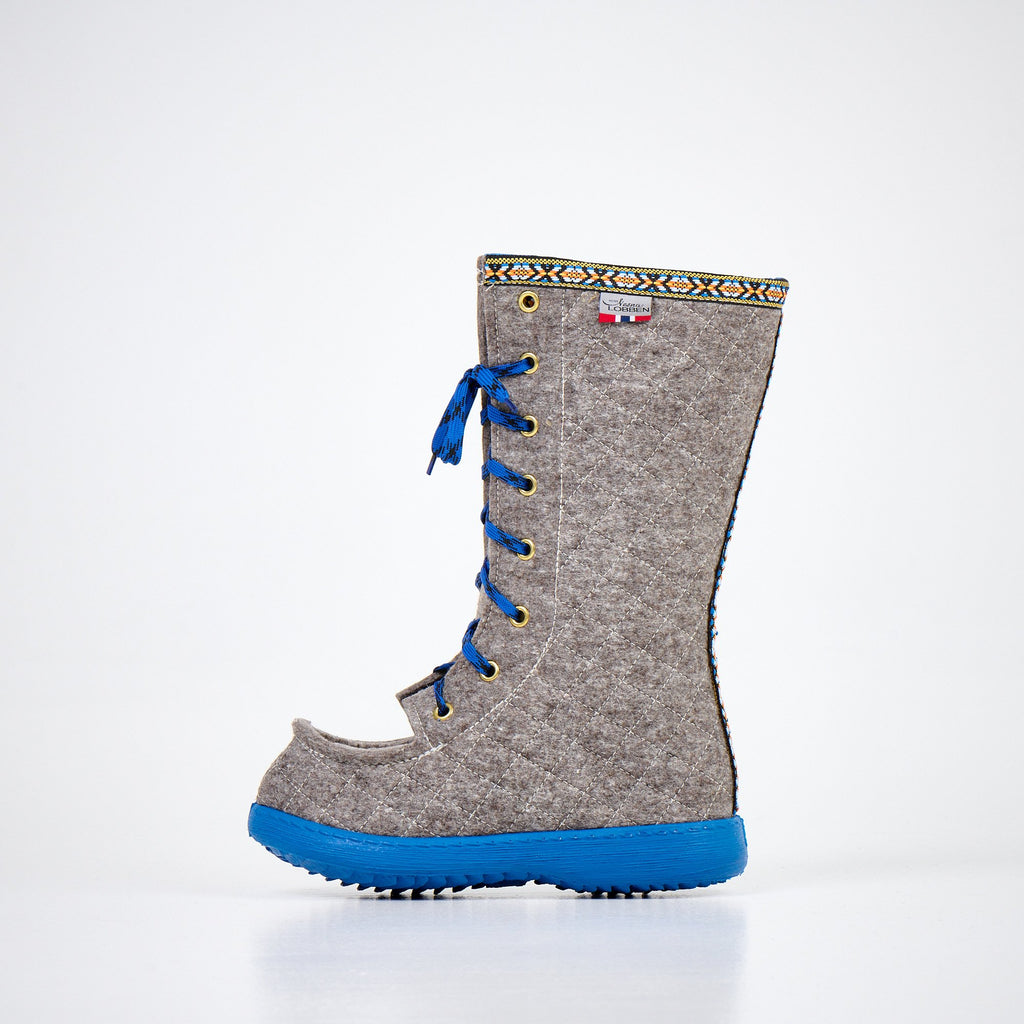3. Side view of Nesna Lobben Polar Lobben Felt Boots in grey with blue laces and soles, studio setting