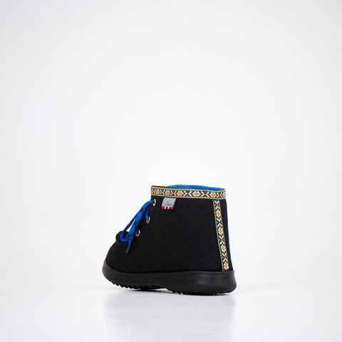 3. Angled view of Nesna Lobben black felt boots with blue laces, showing patterned trim and sole design