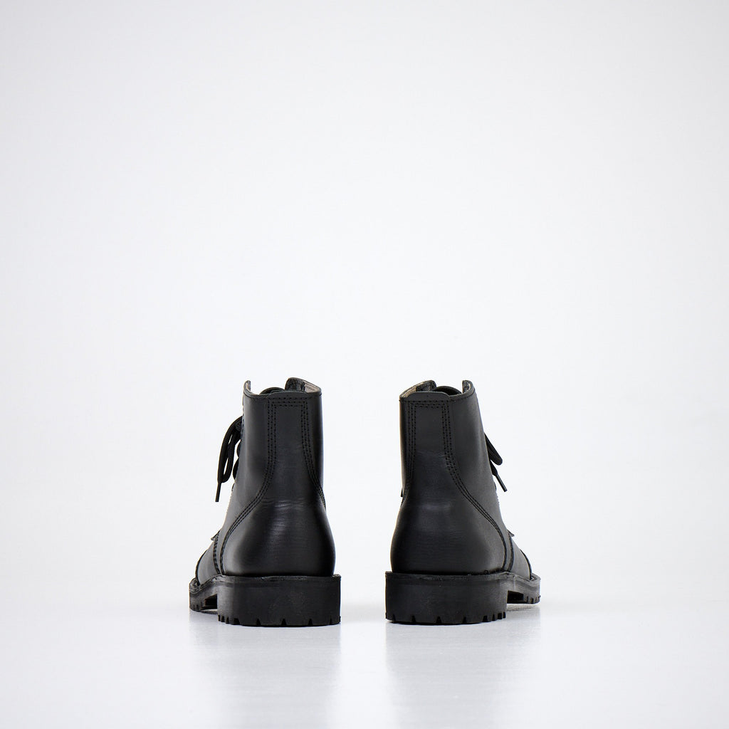 1. Back view of AIPI A-PS-2 black leather boots with lace-up closure, showcasing durable rubber sole in studio setting