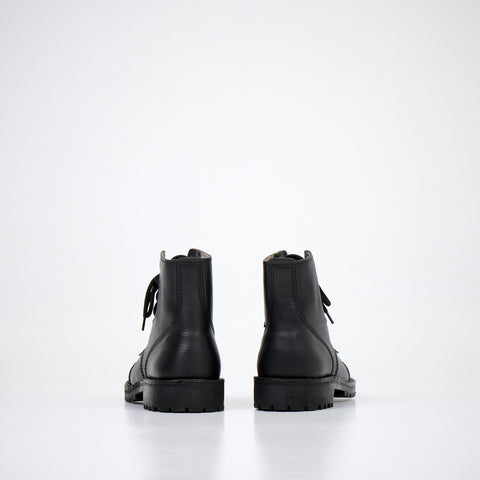 1. Back view of AIPI A-PS-2 black leather boots with lace-up closure, showcasing durable rubber sole in studio setting